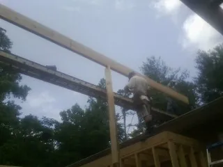 Carpenter setting a ridge beam over a new addition frame — Ice Dam Removal by Roofing Brothers in Horse Branch