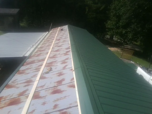 Old rusted panels beside newly installed green metal roofing — Wind Damage Roof Repair by Roofing Brothers in Horse Branch