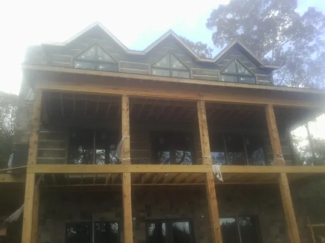 Dormers and porch framing on a large log home under construction — Roof Coating work by our crew in Horse Branch