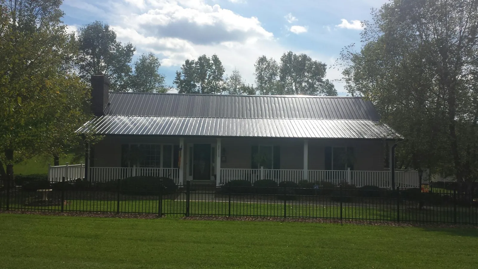 Gray metal roof on a brick ranch with a full width front porch — Gutter Guard Installation work by our crew in Horse Branch
