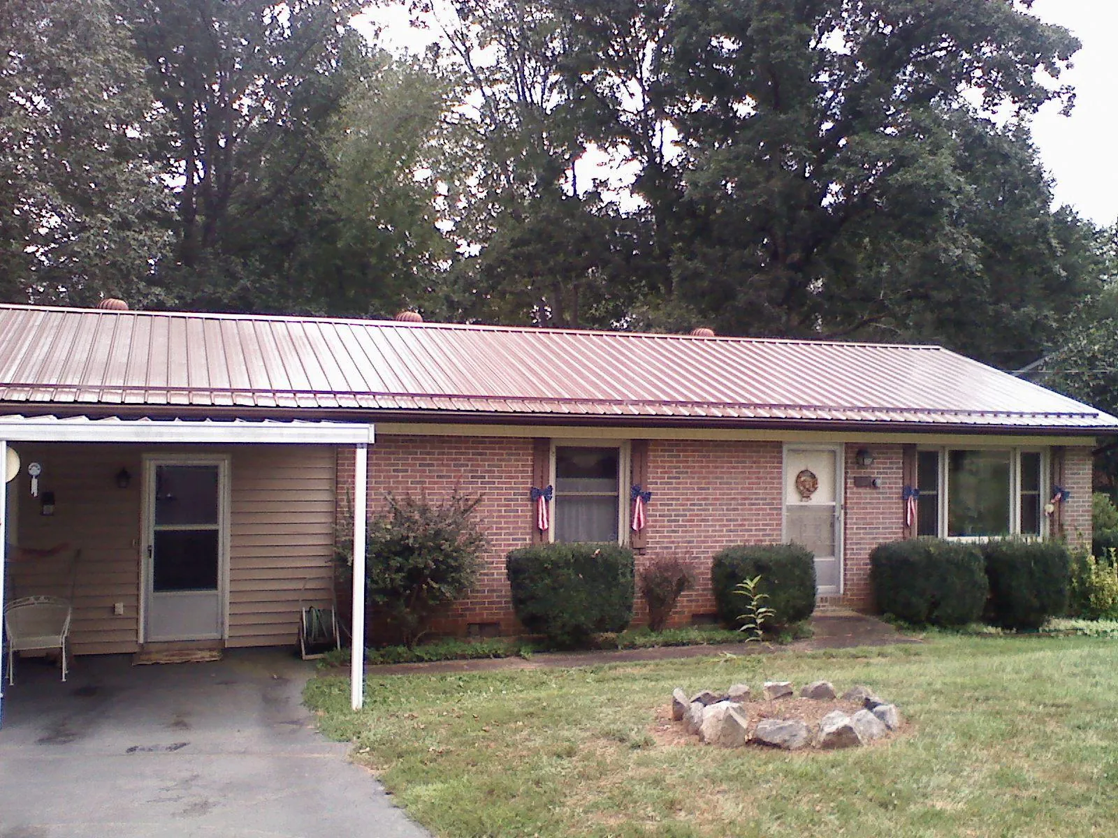 Bronze metal roof and carport on a brick ranch home — Roof Repair work by our crew in Horse Branch