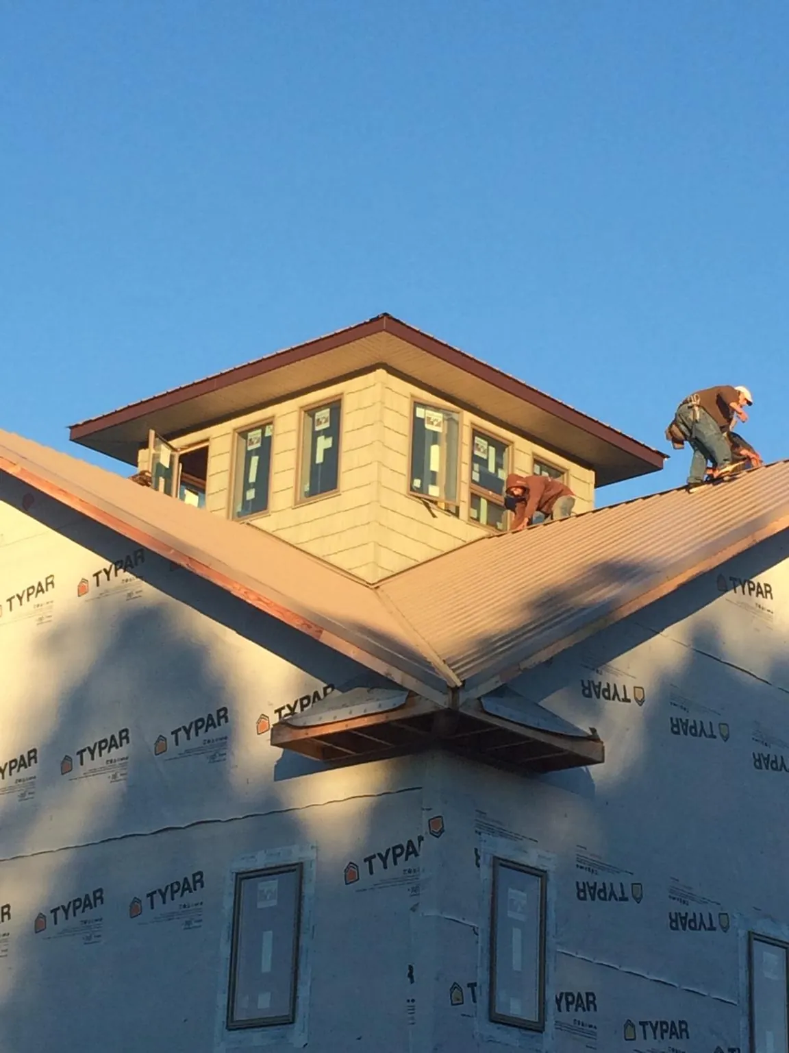 Roofers working around a rooftop cupola on a new metal roof at sunset — Roof Waterproofing in Horse Branch by Roofing Brothers